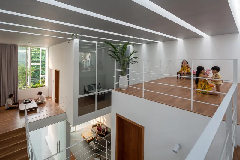 Double-height interior with horizontal ceiling skylights casting linear shadows across white walls and timber flooring