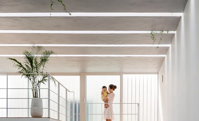 Upper level mezzanine with exposed beams and skylight openings where a woman holds a child near railing