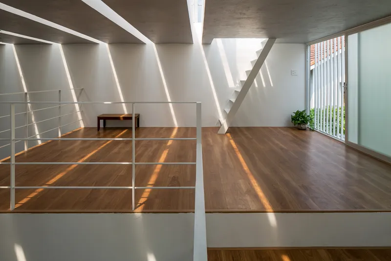 Wood-floored mezzanine with white metal railing and diagonal light stripes from overhead skylights