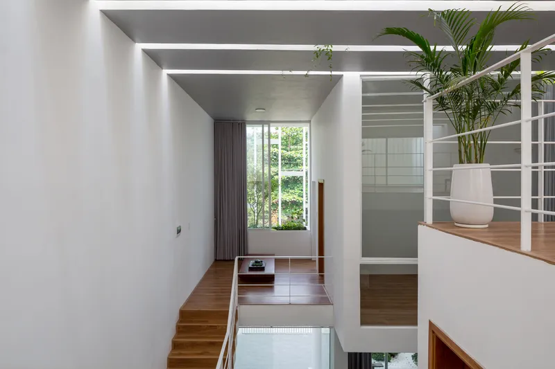 Split-level interior with timber staircase connecting bedroom to open mezzanine beneath parallel skylights