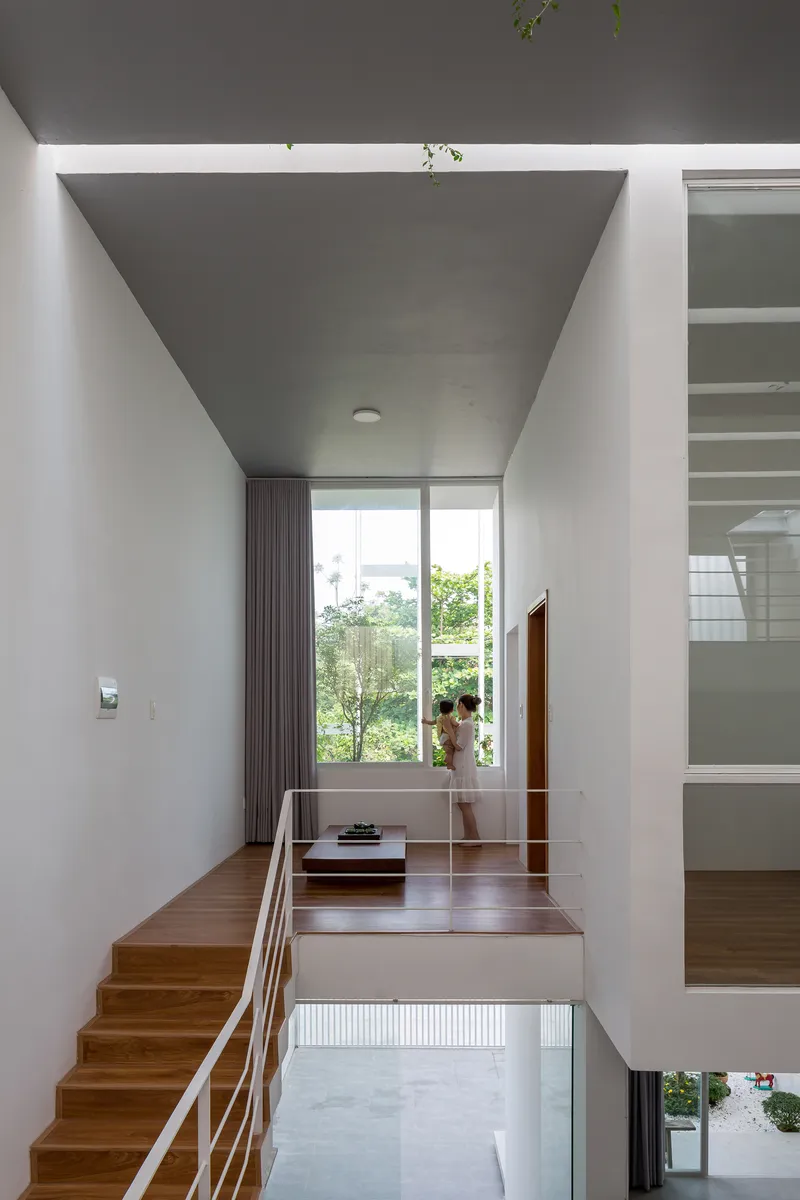 Multi-level interior showing timber staircase with metal railing and glazed volumes overlooking lower floor