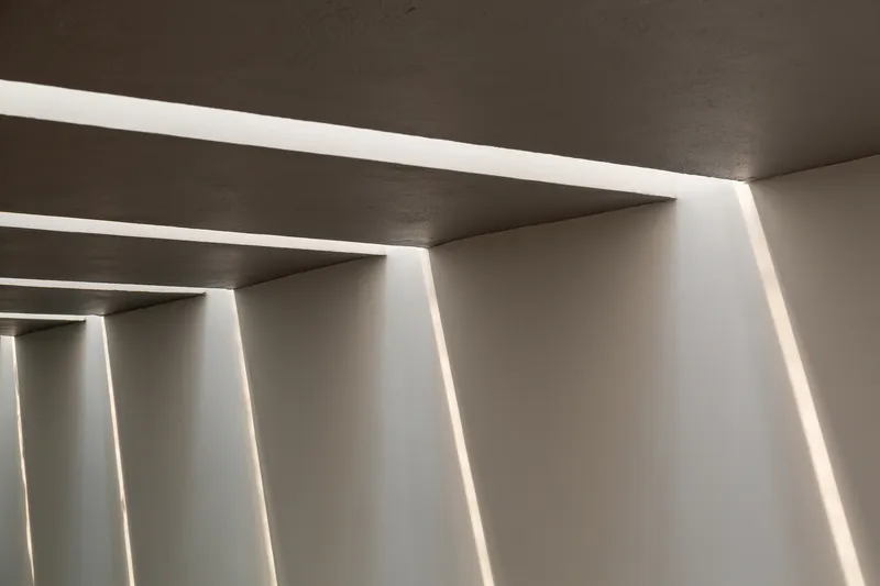Close-up of recessed linear ceiling lights creating parallel bands of illumination across concrete soffit