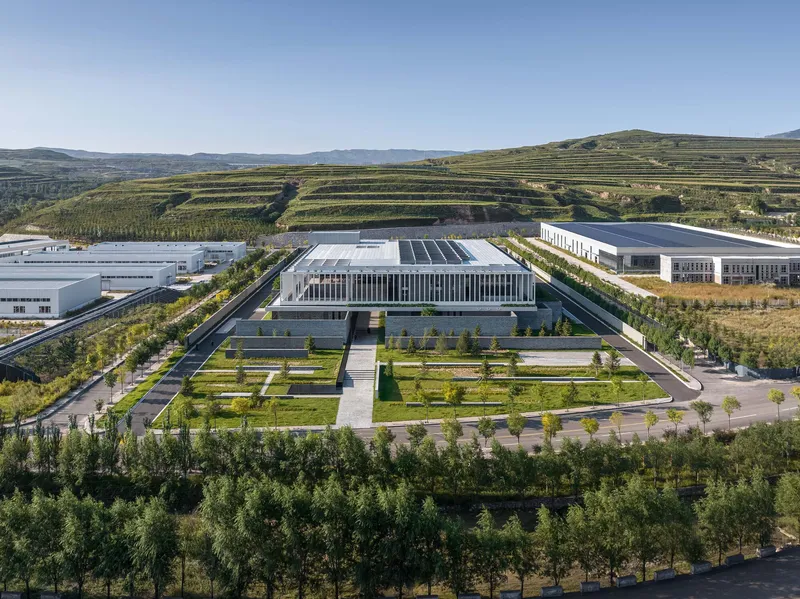 Elevated view of the rectangular building with solar panels and geometric courtyard gardens fronted by tree plantings