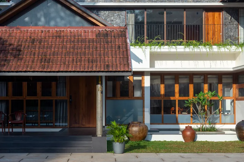 Courtyard view with clay tile roof, glazed facade with timber mullions, and planted balcony above