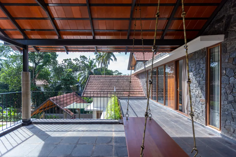 Covered terrace with timber ceiling grid, hanging swing, and view of tiled roofs beyond