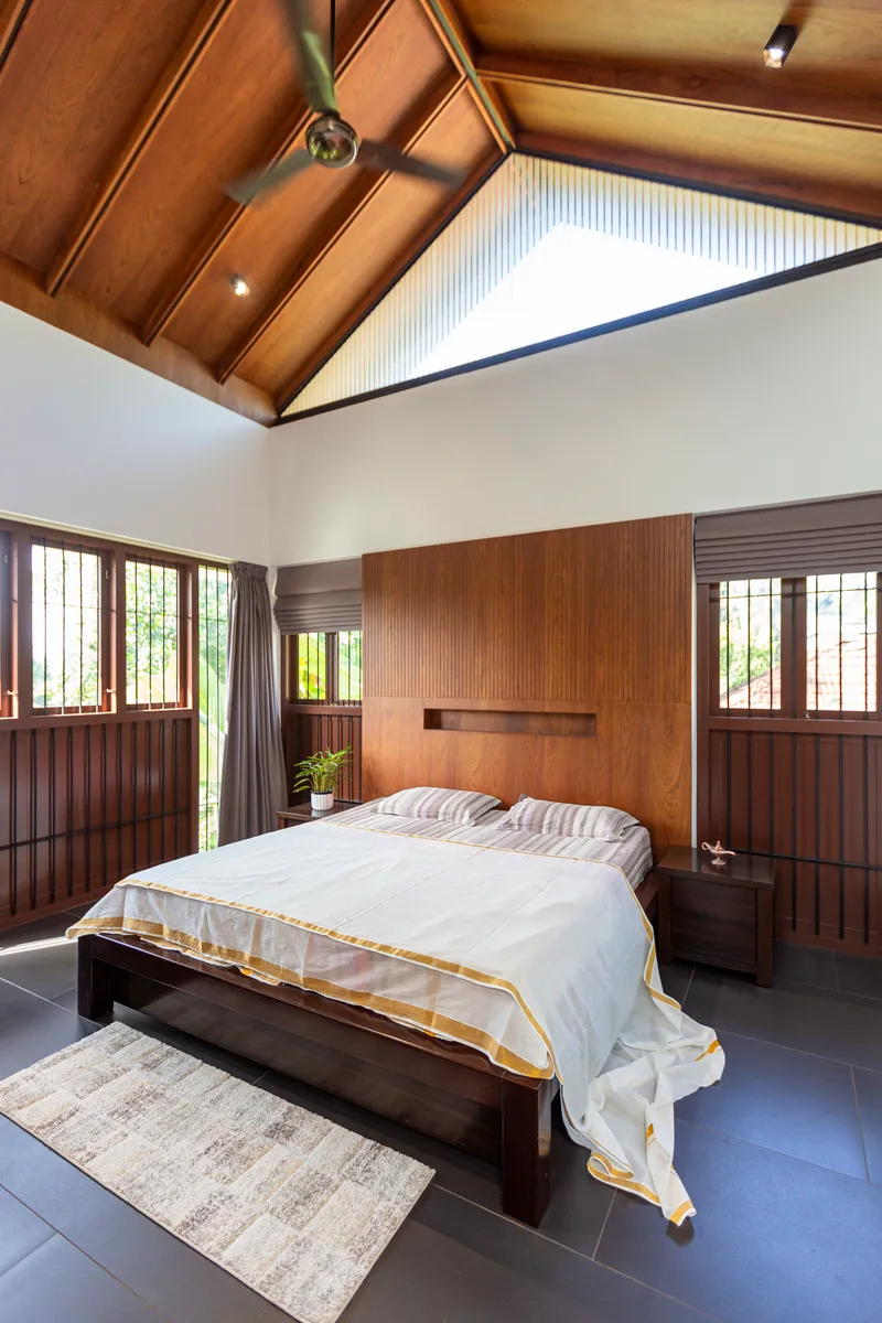 Bedroom with vaulted timber ceiling, wood-paneled walls, and symmetrical windows on either side
