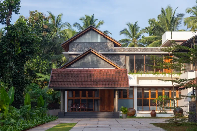 Evening view of the entrance facade with interior lights glowing through timber-framed windows