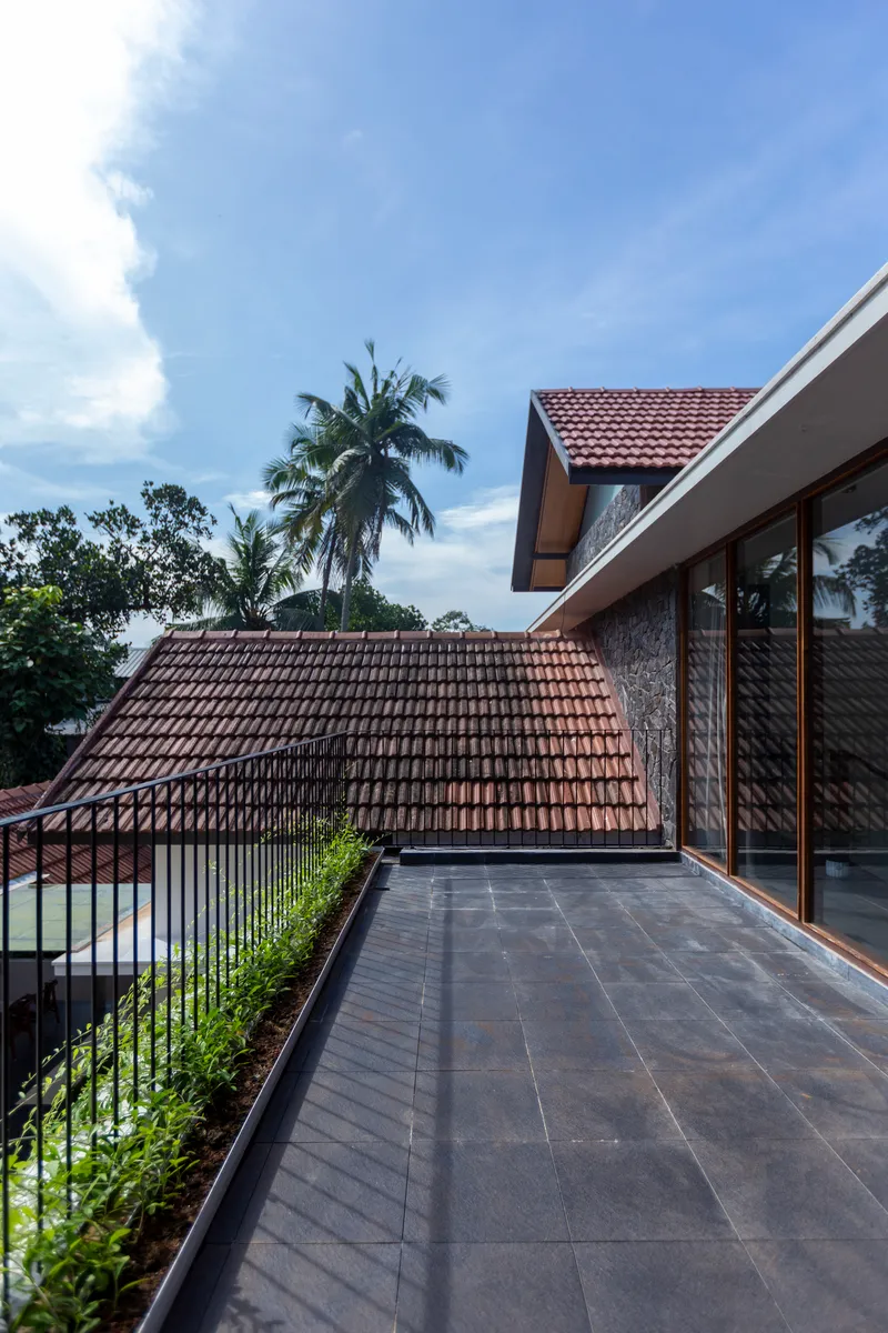 Upper terrace overlooking the clay tile roof with coconut palms against a blue sky