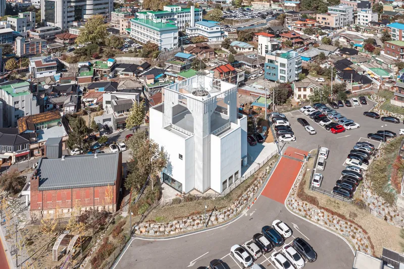 Aerial view of the white tower and adjacent brick structure surrounded by parking lots and residential neighborhood