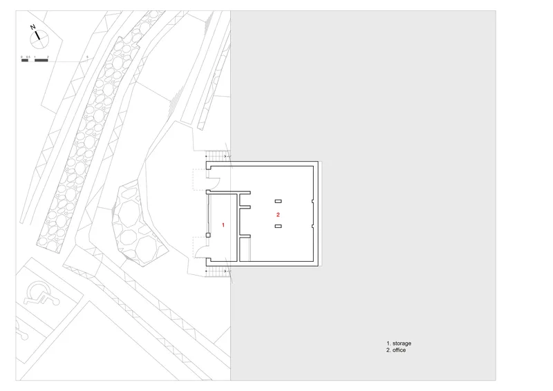 Site plan showing a rectangular building volume adjacent to landscaped areas and diagonal pathways