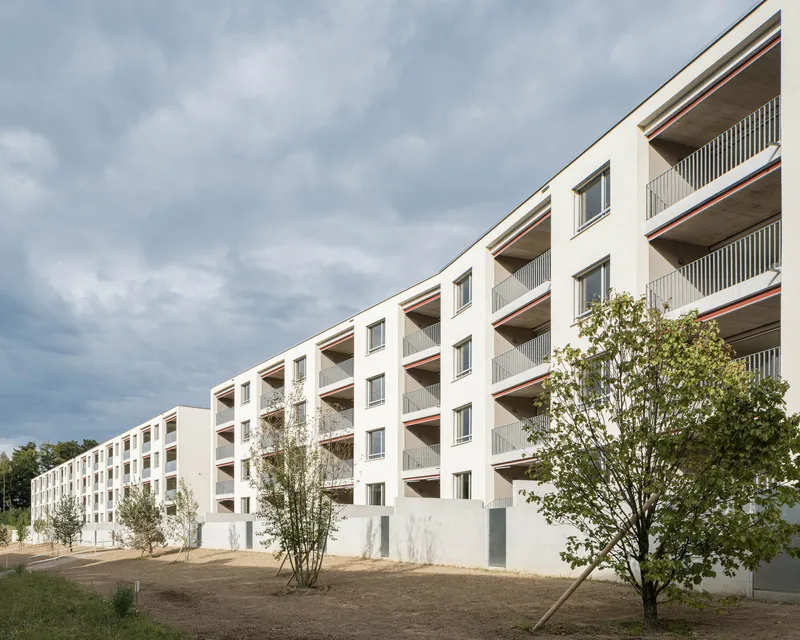 White stucco facade with recessed balconies and vertical slat railings under an overcast sky