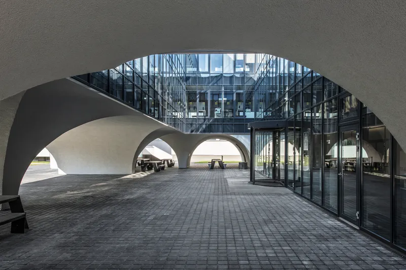 View through curved arch to glazed facade and covered passageway with layered arched openings