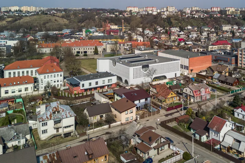 Aerial view of the white perforated volume rising above surrounding residential rooftops in early spring