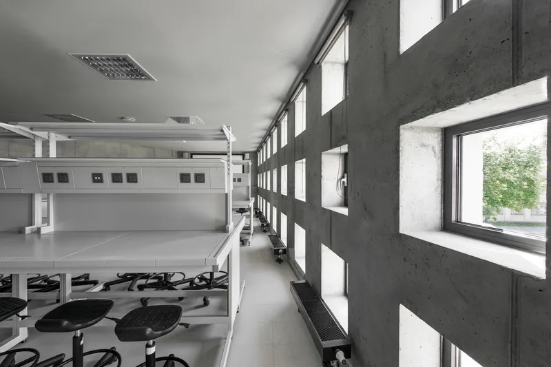 Corridor with perforated concrete block wall filtering daylight beside open workroom