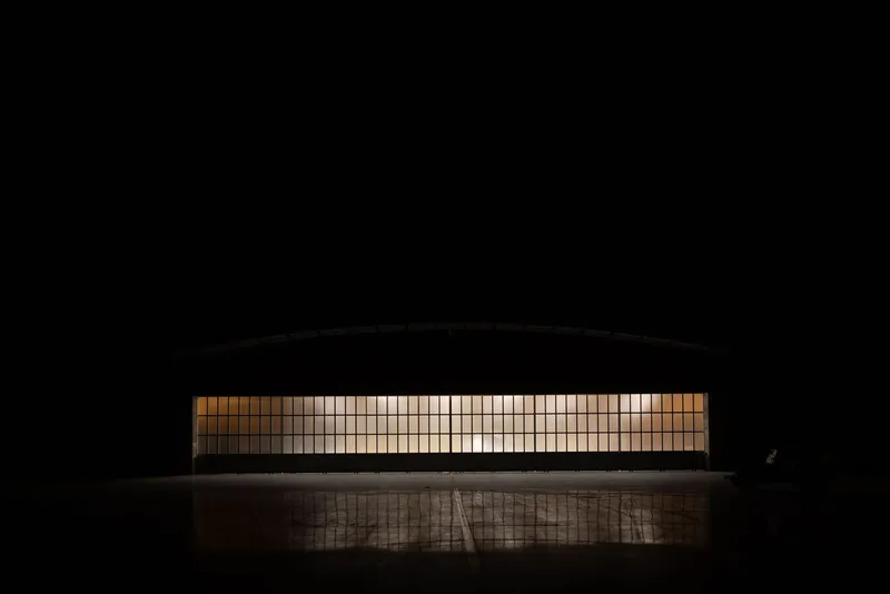 Night view of the illuminated glass block facade with a figure standing at the entrance