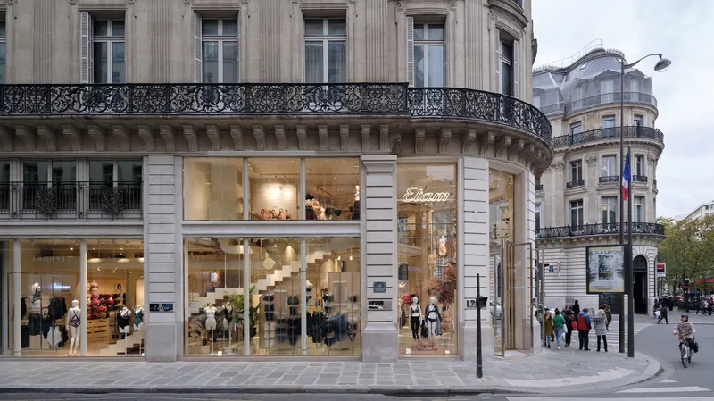 Ground floor storefront with large glazed openings set within rusticated stone facade under overcast sky