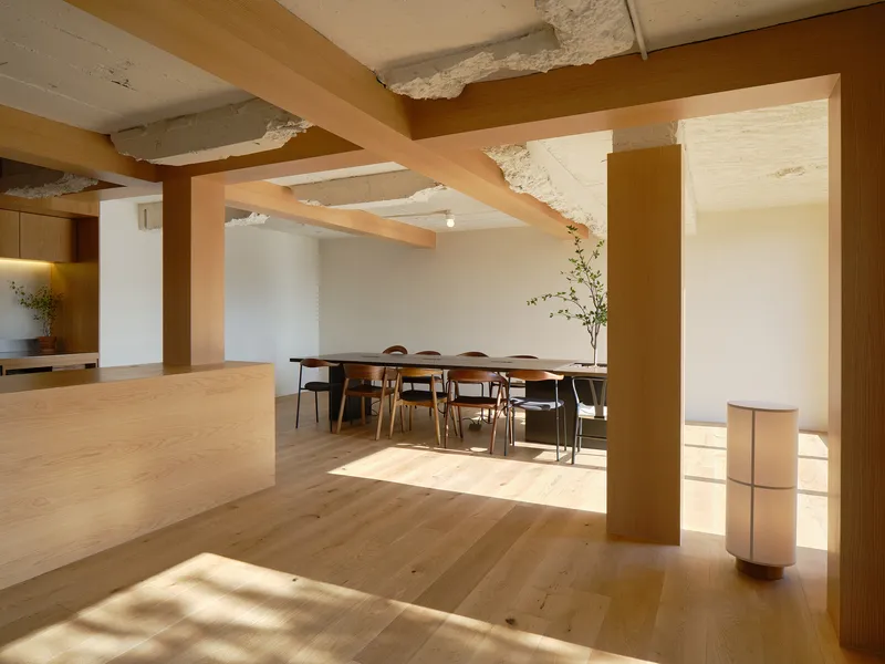 Open living space with exposed timber beams and retained concrete ceiling in afternoon sunlight