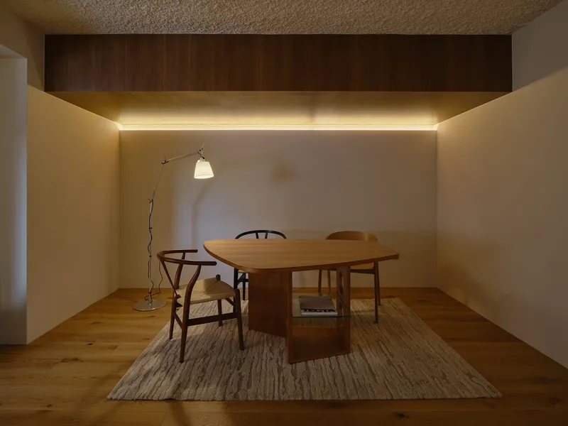 Small dining area with cove lighting beneath a recessed timber ceiling panel at night