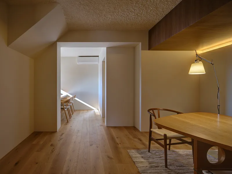 Interior hallway with oak flooring and sloped ceiling leading to a dining space beyond
