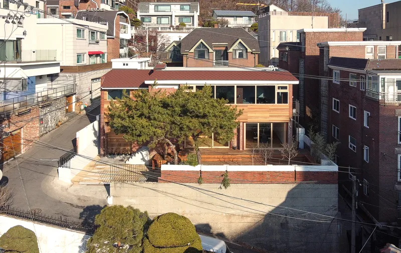 Elevated view of the residence with flat roof and surrounding residential context on a winter day