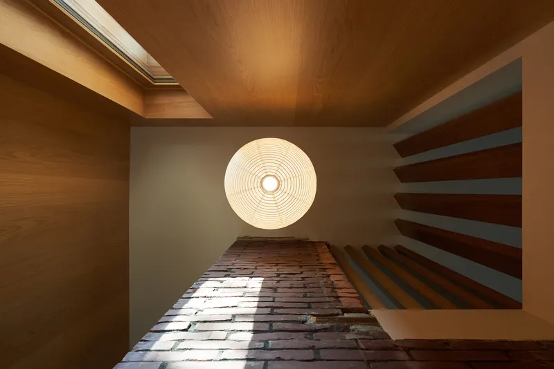 Looking up the stairwell with alternating timber treads and circular ceiling light fixture above