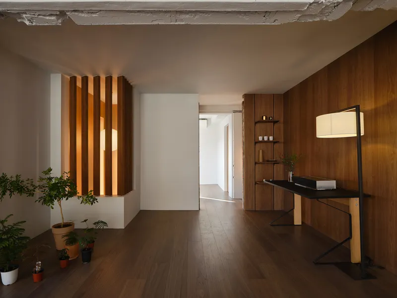 Interior hallway with backlit timber slat screen and walnut paneling adjacent to potted plants on the floor