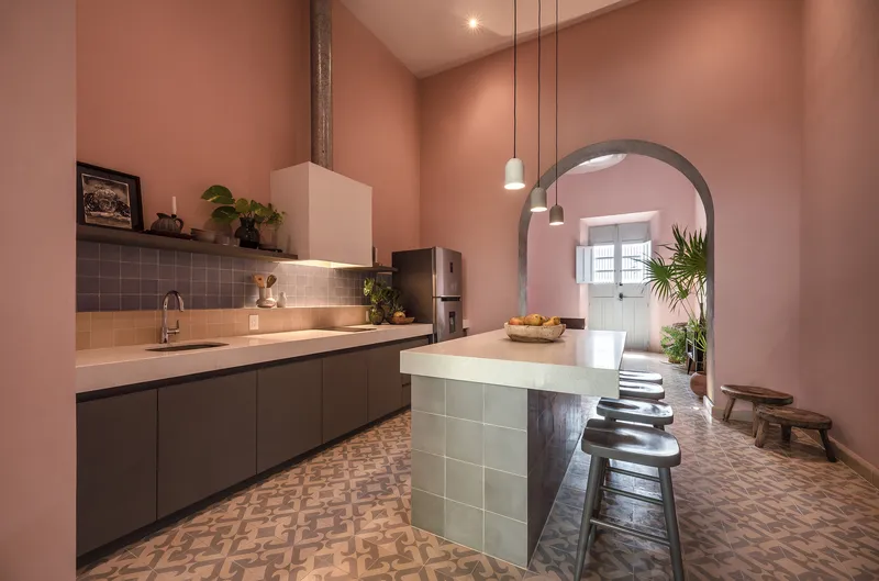 Kitchen with pink plaster walls, patterned tile floor, and arched passage leading to adjacent room
