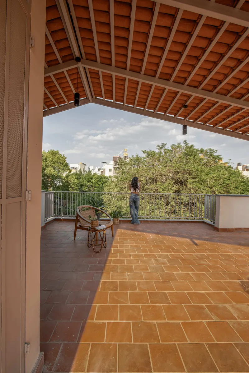 Rooftop terrace with herringbone terracotta tile floor and exposed timber rafter ceiling framing the tree canopy beyond
