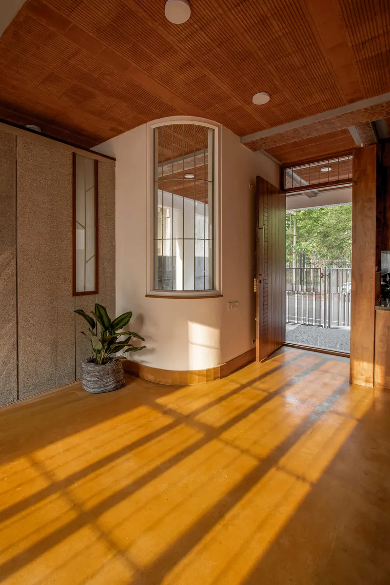 Arched window alcove with amber concrete floor casting long shadow bars from the gridded glazing in morning light