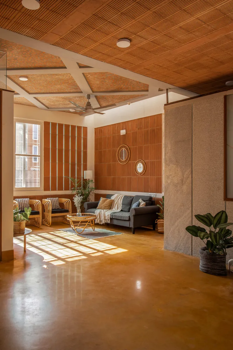 Living area with coffered cork ceiling panels, timber wall cladding, and afternoon light filtering through the windows