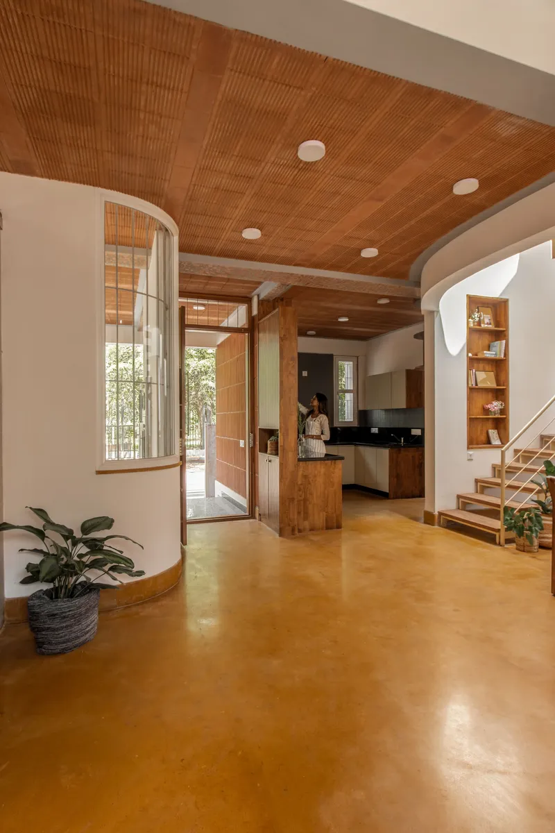 Open living area with vaulted timber ceiling, polished ochre floor, arched doorways and potted plants