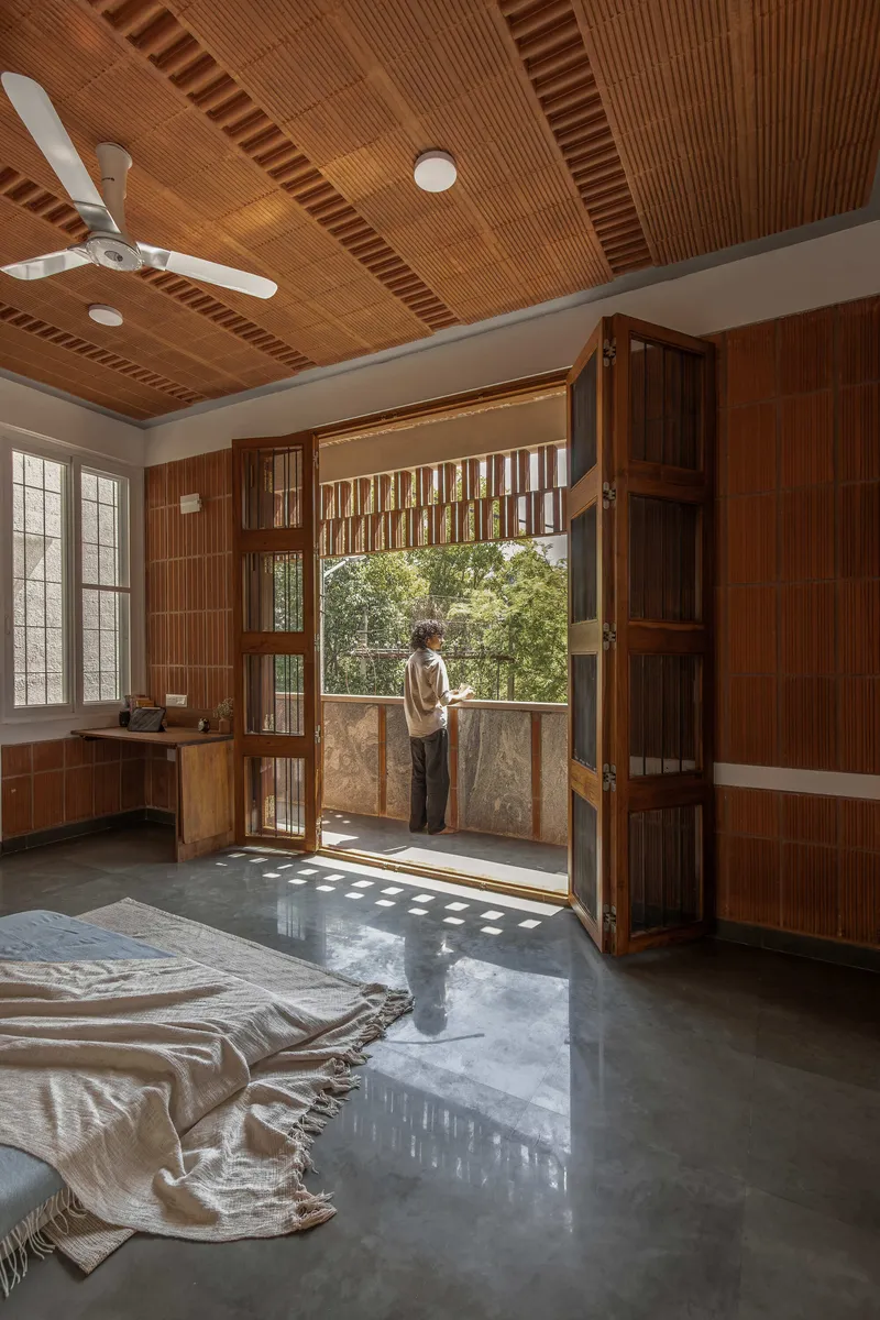Bedroom with timber wainscoting, folding wooden doors opening to a balcony and patterned sunlight on polished floor