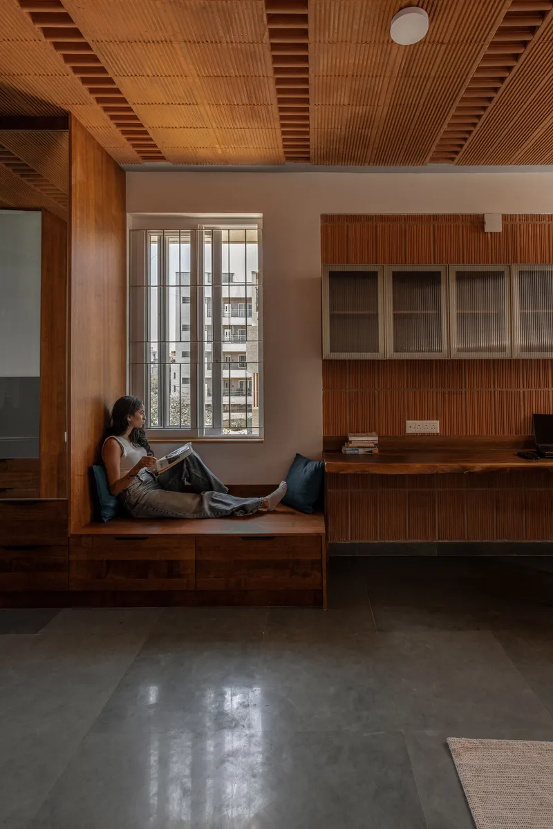 Reading nook with timber bench seat and slatted wooden ceiling beside tall gridded windows