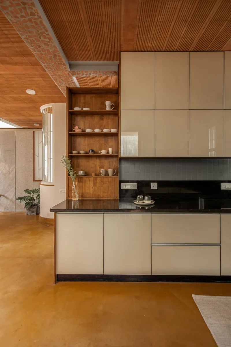 Kitchen with beige lacquered cabinets, black countertop and timber ceiling with exposed brick detail