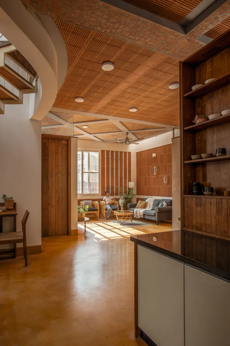View through arched opening into living area with diagonal timber slat ceiling and afternoon sunlight flooding the floor