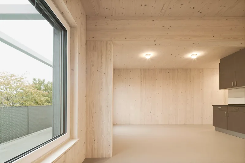 Interior room with exposed light timber plank walls and ceiling, cream flooring and a built-in grey kitchenette