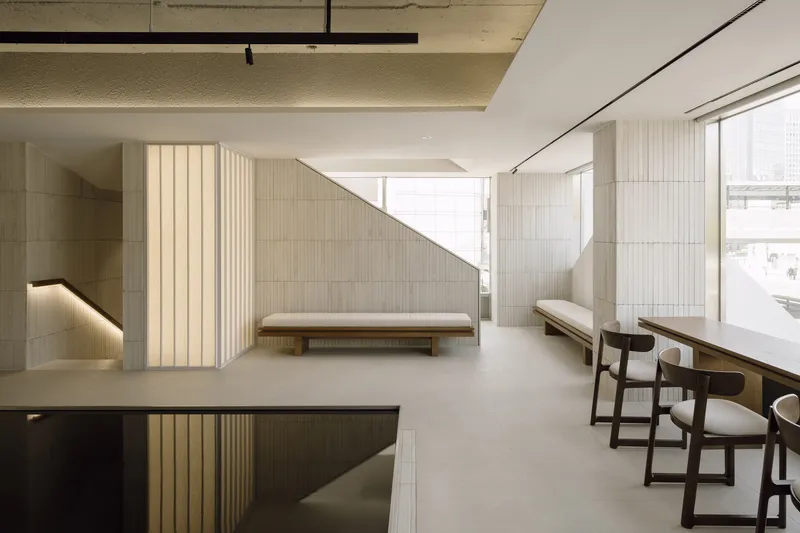 Angled timber partition with integrated lighting beside seating benches and window views of adjacent buildings