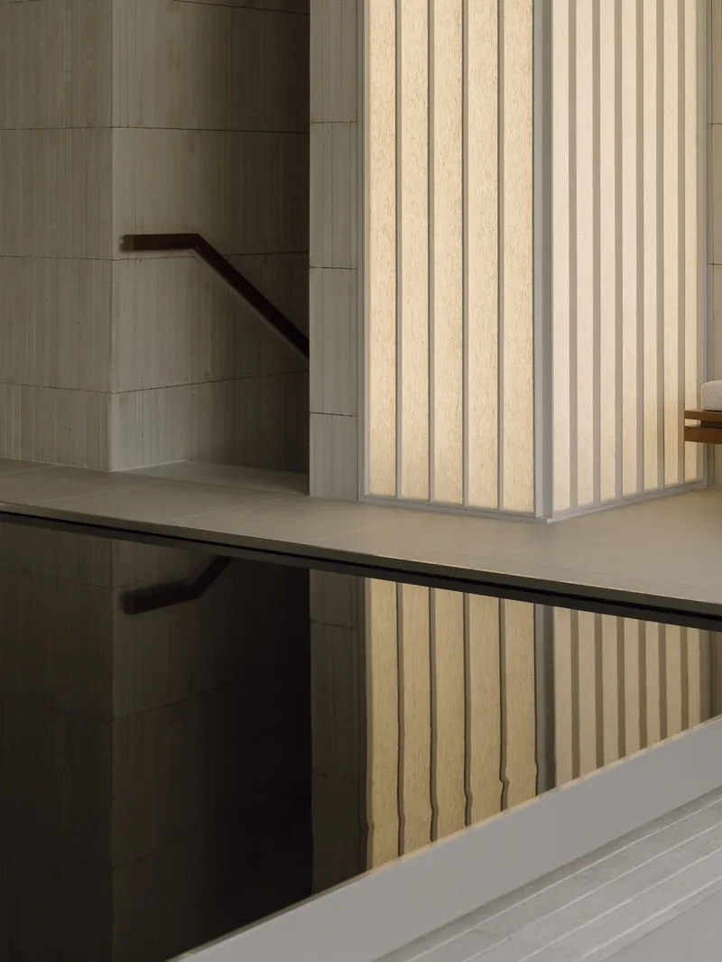 Interior stairwell with vertical timber cladding and black metal handrails spanning multiple levels
