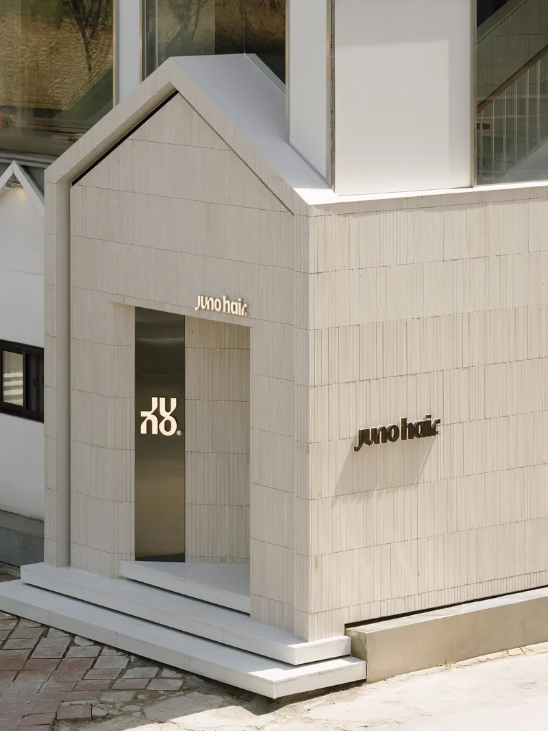 Street corner facade with gabled volume clad in vertical timber strips and recessed glass entrance