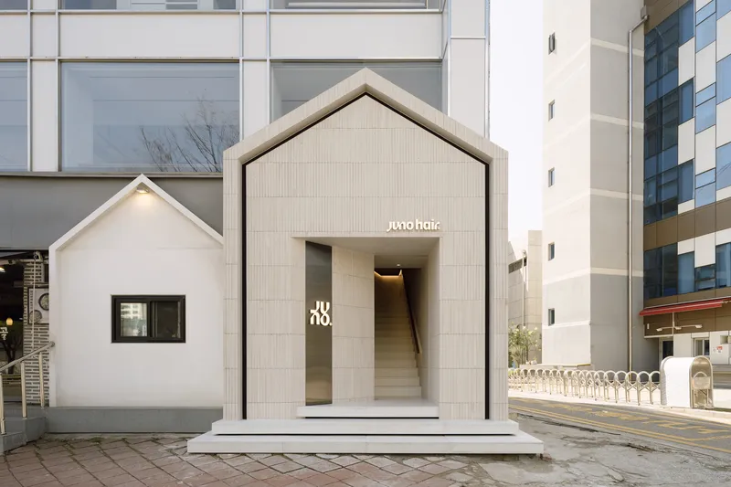 Exterior view of gabled timber pavilion inserted between existing buildings on cobblestone street