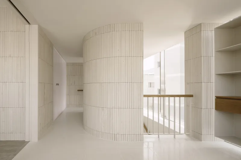 Curved ribbed tile volume around window opening with timber railing and daylight streaming in