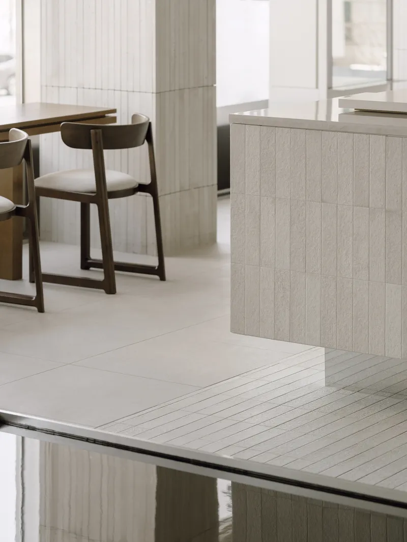 Detail of the junction between pale tiled salon counter and reflective dark glass surface