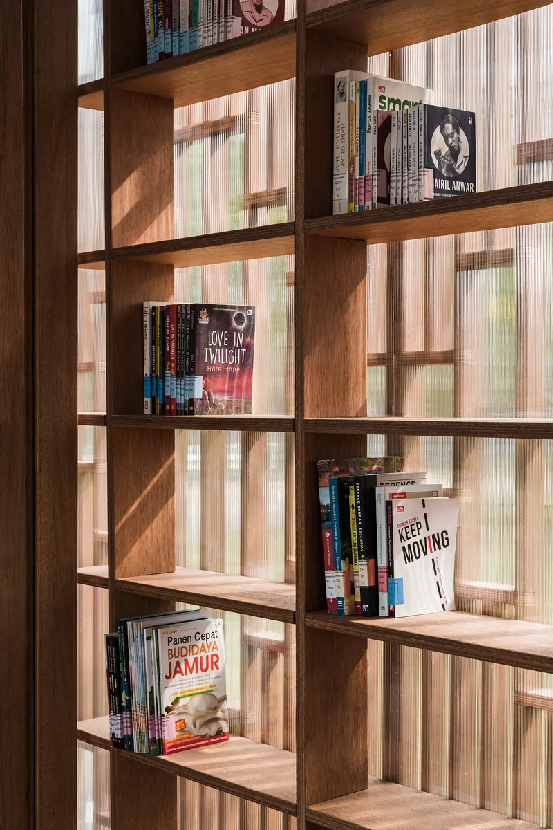Wooden shelving units displaying books against a backdrop of translucent corrugated wall panels