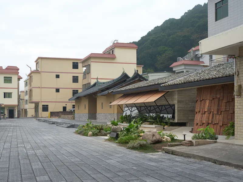 Curved gabled roof structure with timber shingles and planted beds fronting a residential street