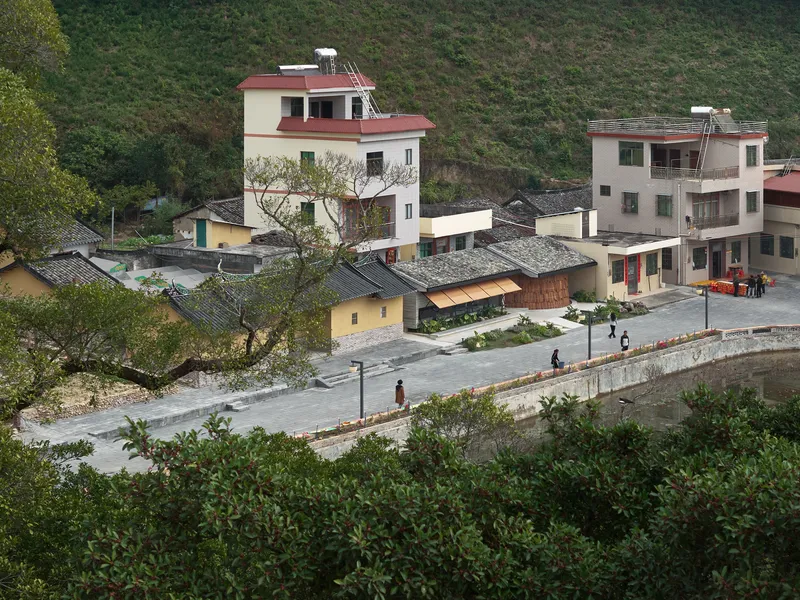 Hillside village cluster with traditional tile roofs and a curving waterfront wall