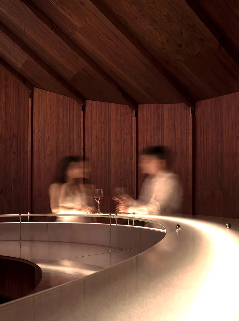 Curved counter with integrated lighting under timber ceiling with blurred figures in motion