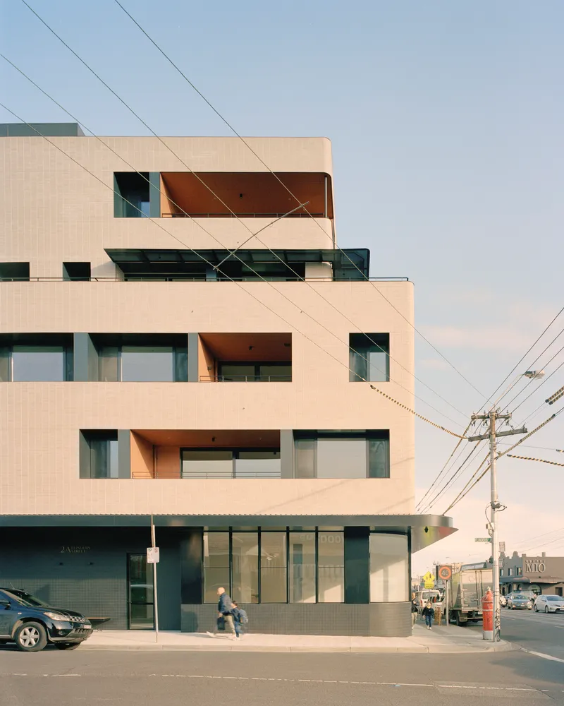 Street view of the light tile facade with recessed terraces and overhead power lines