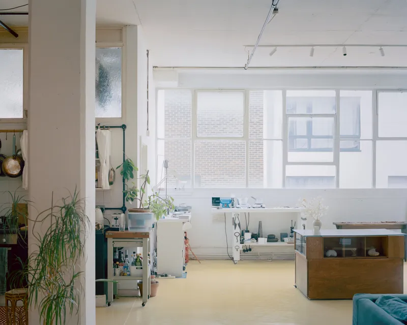 Studio space with yellow flooring, gridded windows, and freestanding furniture bathed in diffuse daylight