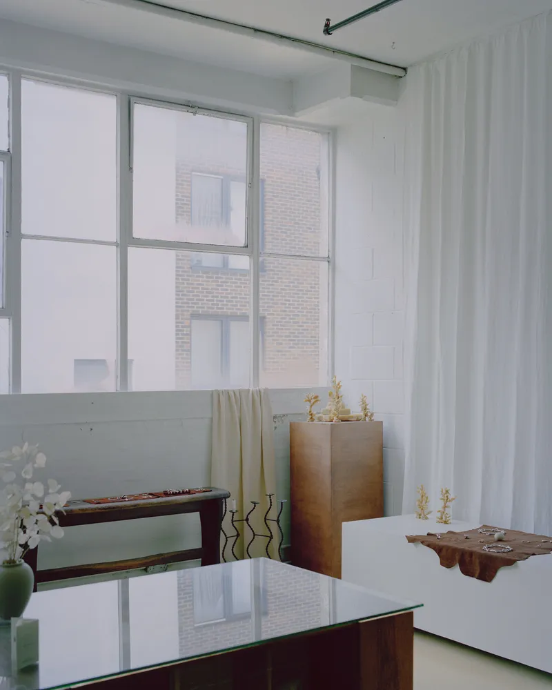 Interior corner with glass table, wood storage cabinet, and translucent curtain dividing the space