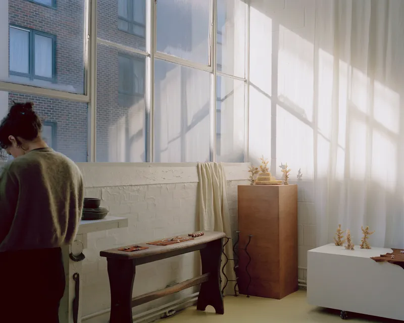 Gallery space with white brick partition wall and tall industrial windows casting afternoon shadows